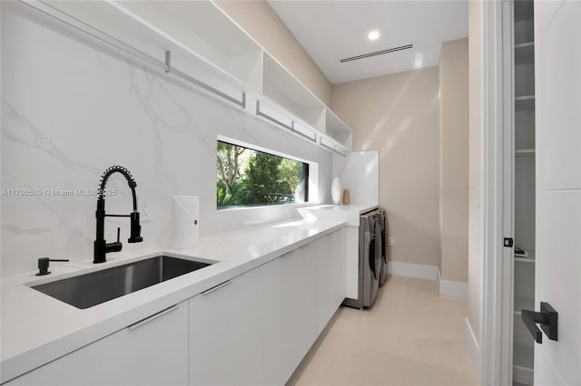 washroom with washer / dryer, sink, and light tile patterned floors