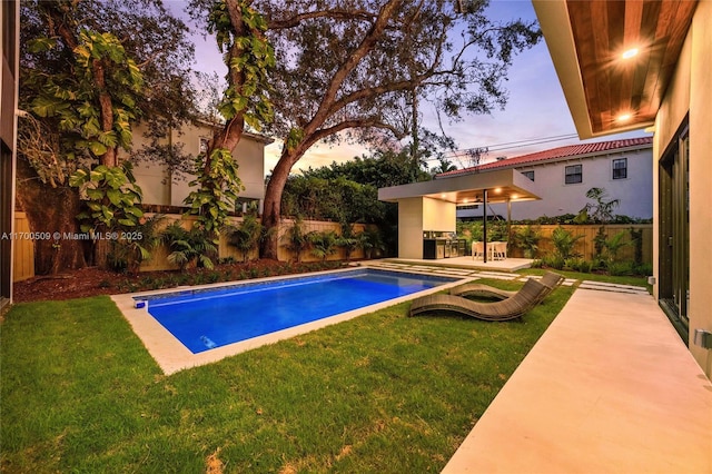 pool at dusk with a lawn and a patio area