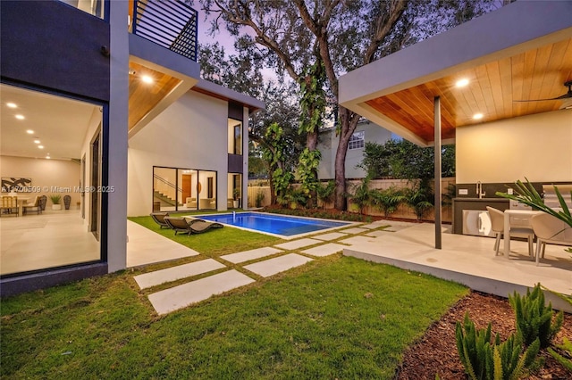 view of pool with exterior kitchen, a yard, and a patio area