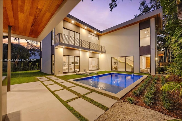 pool at dusk with a patio area