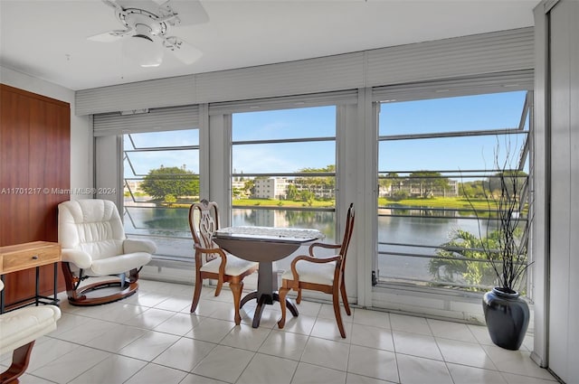 sunroom featuring ceiling fan, a healthy amount of sunlight, and a water view