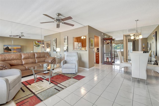 living room with ceiling fan with notable chandelier, light tile patterned floors, and a textured ceiling