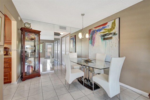 dining space with light tile patterned flooring, a textured ceiling, and a chandelier