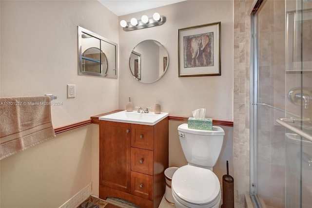 bathroom featuring vanity, toilet, and a shower with shower door