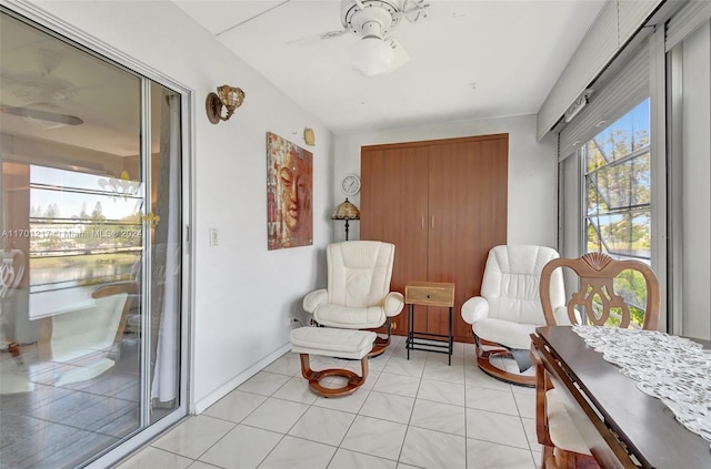 living area featuring a water view, ceiling fan, and light tile patterned floors