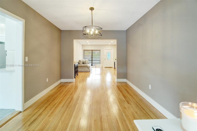 unfurnished dining area featuring a chandelier and wood-type flooring