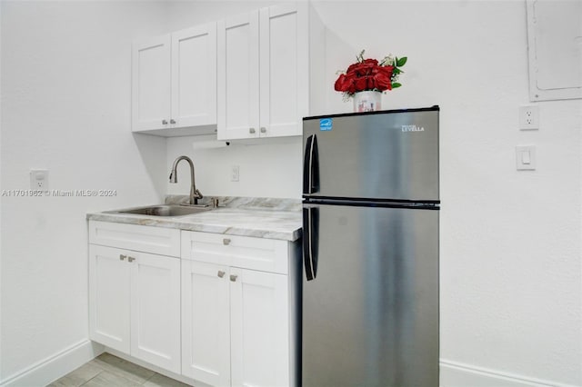 kitchen featuring stainless steel fridge, sink, and white cabinets