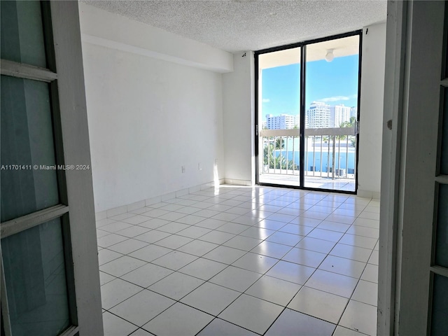 tiled empty room featuring a textured ceiling and french doors