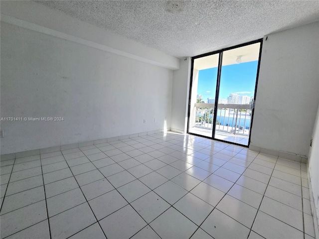 tiled empty room featuring a textured ceiling