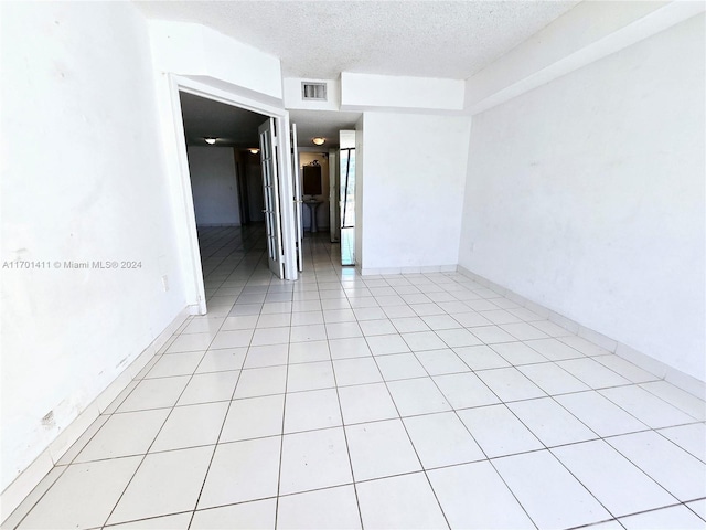 tiled empty room with a textured ceiling