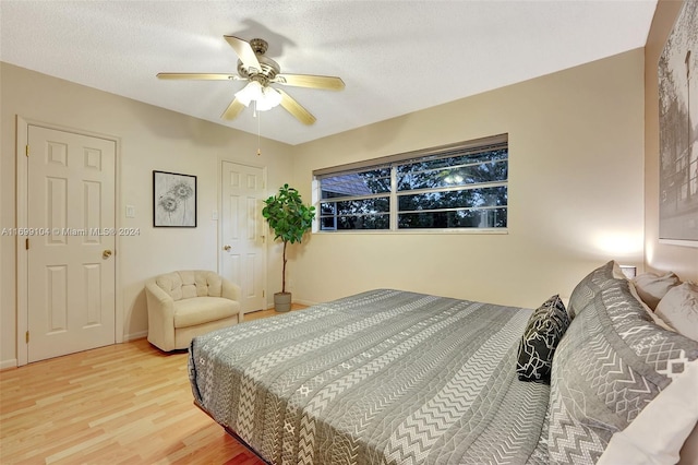 bedroom with ceiling fan, wood-type flooring, and a textured ceiling