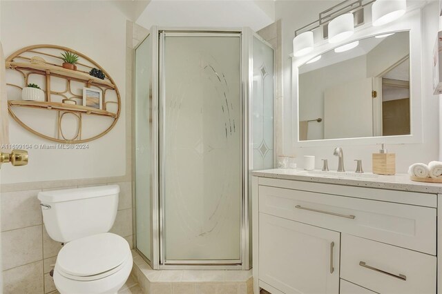 bathroom featuring vanity, toilet, walk in shower, and tile walls