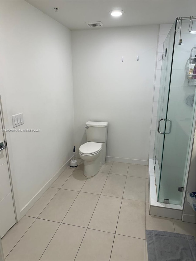 bathroom featuring toilet, tile patterned floors, and a shower with door