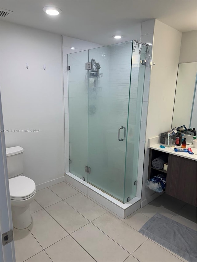 bathroom with tile patterned flooring, vanity, an enclosed shower, and toilet