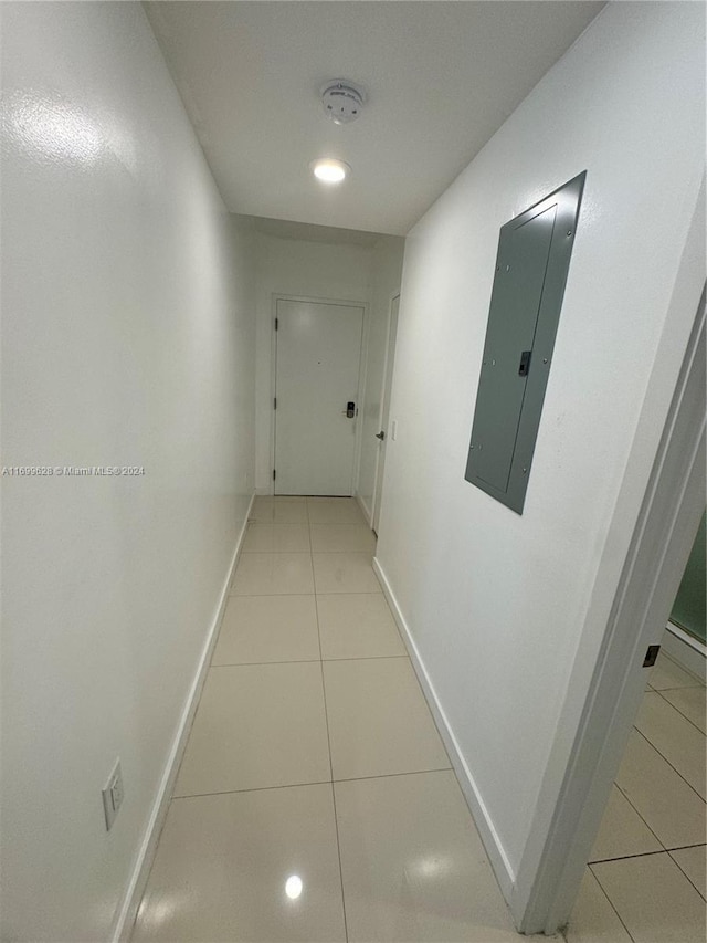 hall with light tile patterned floors and electric panel