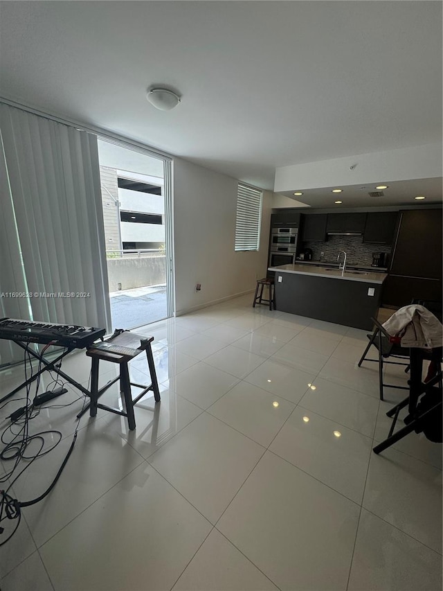 unfurnished living room featuring light tile patterned floors and sink