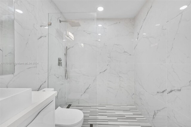 bathroom with a tile shower, vanity, and toilet