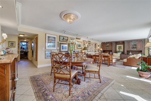 dining space with crown molding, light tile patterned flooring, and track lighting