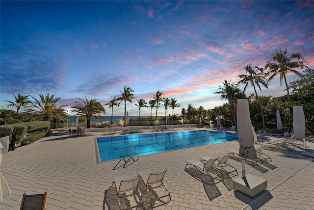 pool at dusk featuring a patio area