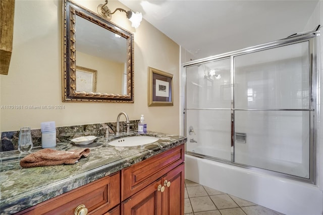 bathroom featuring tile patterned flooring, vanity, and combined bath / shower with glass door