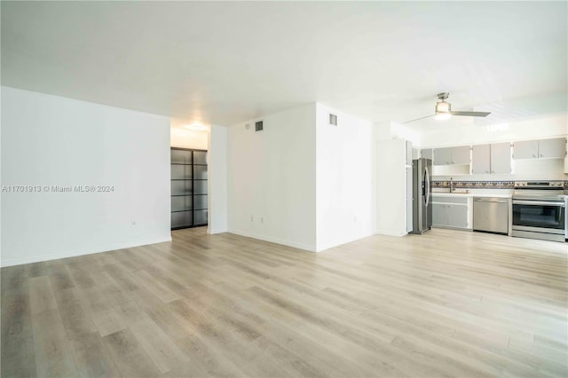 unfurnished living room featuring light hardwood / wood-style flooring, ceiling fan, and sink