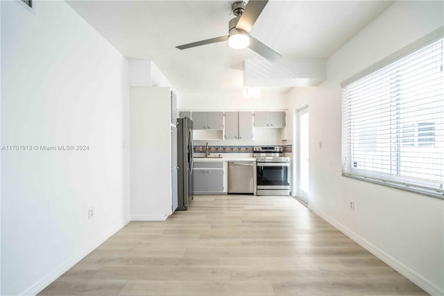 kitchen featuring light hardwood / wood-style floors, stainless steel appliances, ceiling fan, sink, and gray cabinets