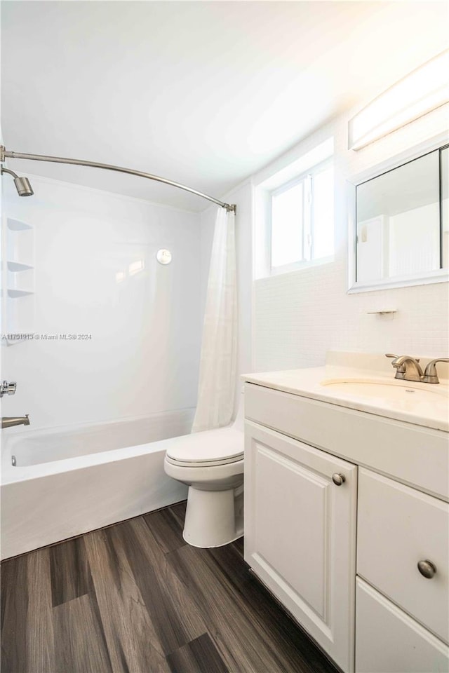 full bathroom featuring hardwood / wood-style flooring, shower / bath combination with curtain, toilet, and vanity