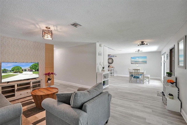 living room with light hardwood / wood-style floors and a textured ceiling