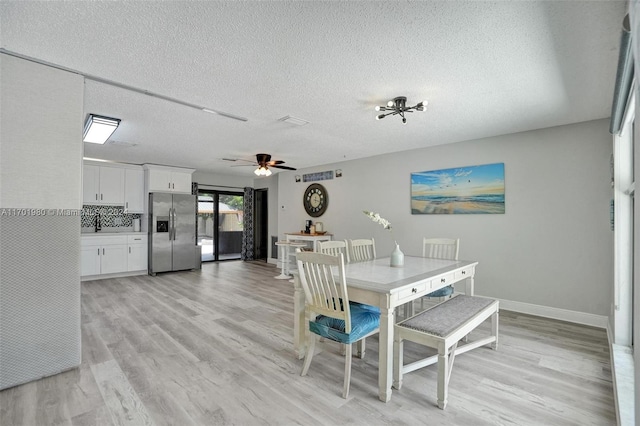 dining room featuring ceiling fan, light wood-type flooring, and a textured ceiling