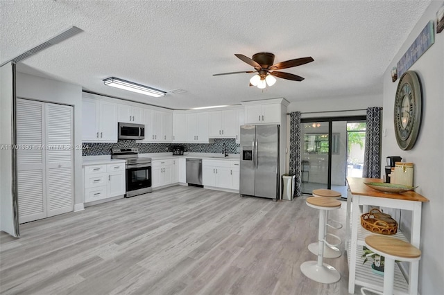 kitchen with ceiling fan, light hardwood / wood-style flooring, white cabinets, and appliances with stainless steel finishes