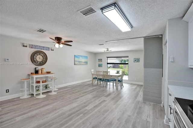 dining room featuring a textured ceiling, light hardwood / wood-style flooring, and ceiling fan