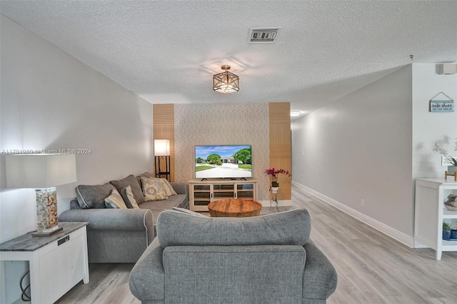 living room with a textured ceiling and light hardwood / wood-style floors