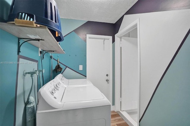 clothes washing area with washing machine and clothes dryer, light hardwood / wood-style flooring, and a textured ceiling