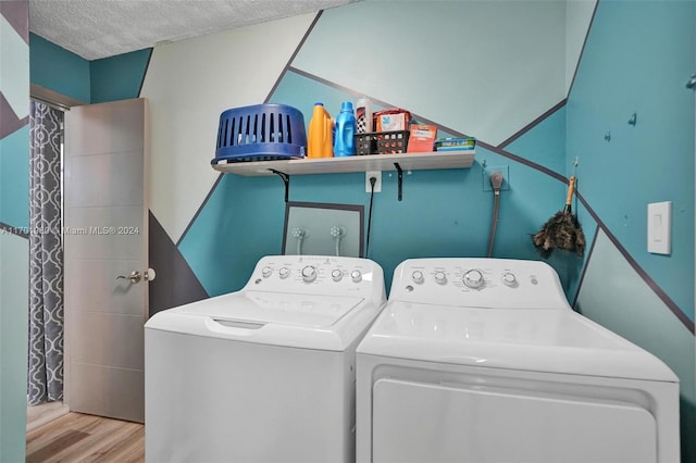 laundry room featuring independent washer and dryer, a textured ceiling, and light hardwood / wood-style flooring