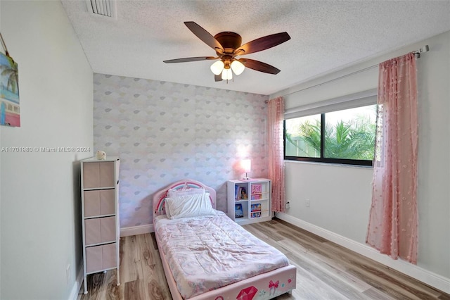 bedroom featuring ceiling fan, light hardwood / wood-style flooring, and a textured ceiling