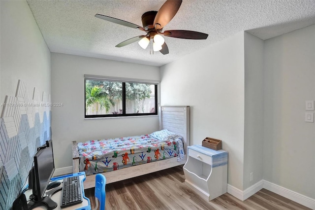 bedroom featuring ceiling fan, wood-type flooring, and a textured ceiling