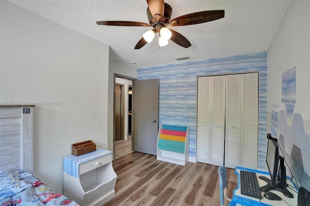 bedroom with ceiling fan, a closet, a textured ceiling, and light hardwood / wood-style flooring