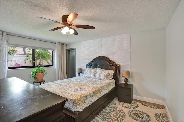 bedroom featuring ceiling fan, light hardwood / wood-style flooring, and a textured ceiling