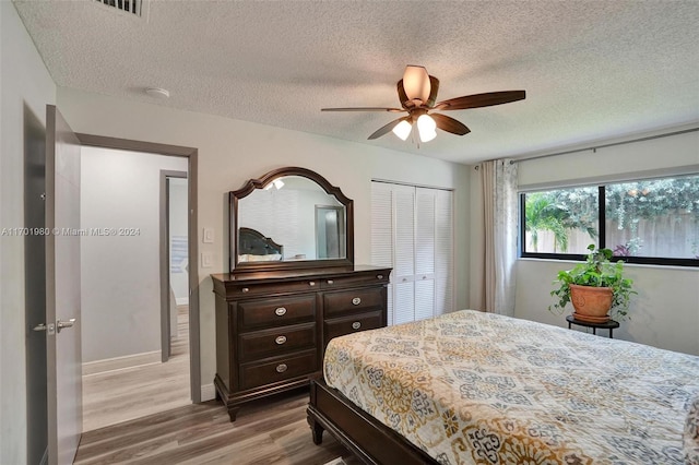 bedroom with a textured ceiling, ceiling fan, light hardwood / wood-style flooring, and a closet