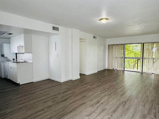 unfurnished living room with a textured ceiling, dark wood-type flooring, and sink