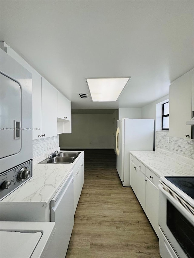 kitchen with stacked washer / dryer, white cabinets, light hardwood / wood-style floors, and white appliances