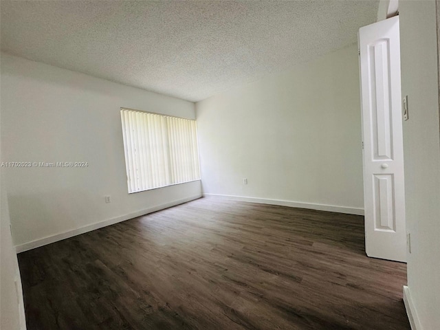 empty room featuring dark wood-type flooring and a textured ceiling