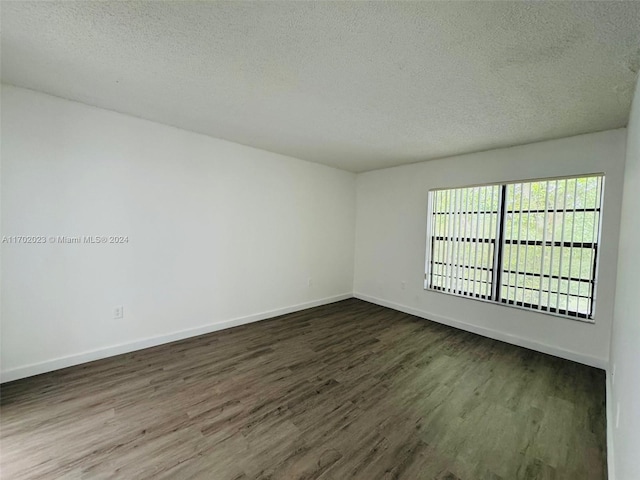 spare room with dark hardwood / wood-style floors and a textured ceiling