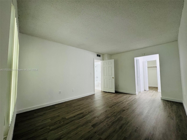 unfurnished room featuring dark hardwood / wood-style flooring and a textured ceiling