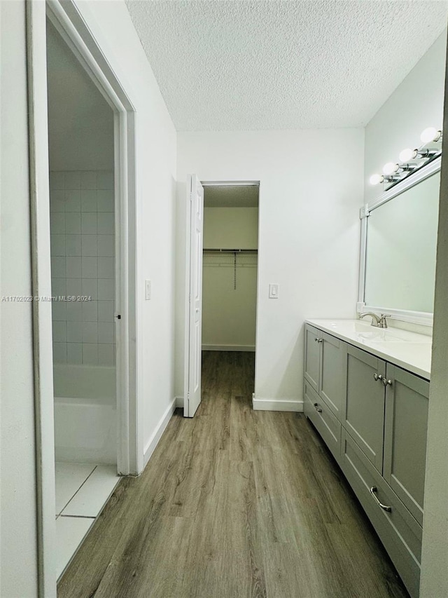 bathroom with hardwood / wood-style floors, vanity, a textured ceiling, and walk in shower