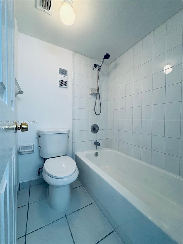 bathroom featuring tile patterned floors, tiled shower / bath combo, and toilet