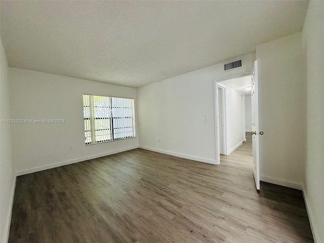 unfurnished room featuring wood-type flooring and a textured ceiling