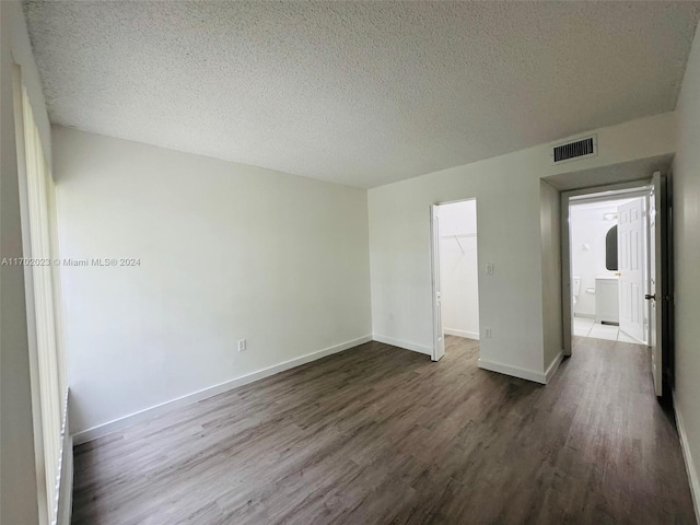 empty room with a textured ceiling and dark wood-type flooring