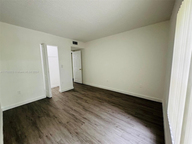 unfurnished bedroom with a textured ceiling and dark hardwood / wood-style flooring