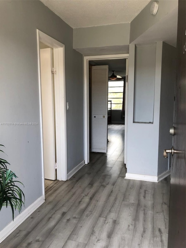 hallway with light wood-type flooring and a textured ceiling